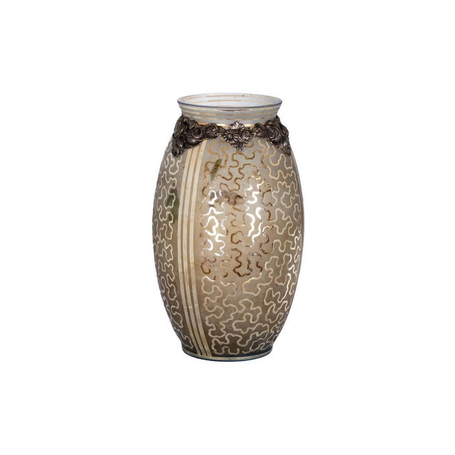 An Art Deco vase with polychrome glass paired with a metal neck adorned with delicate floral motifs. The glass body...