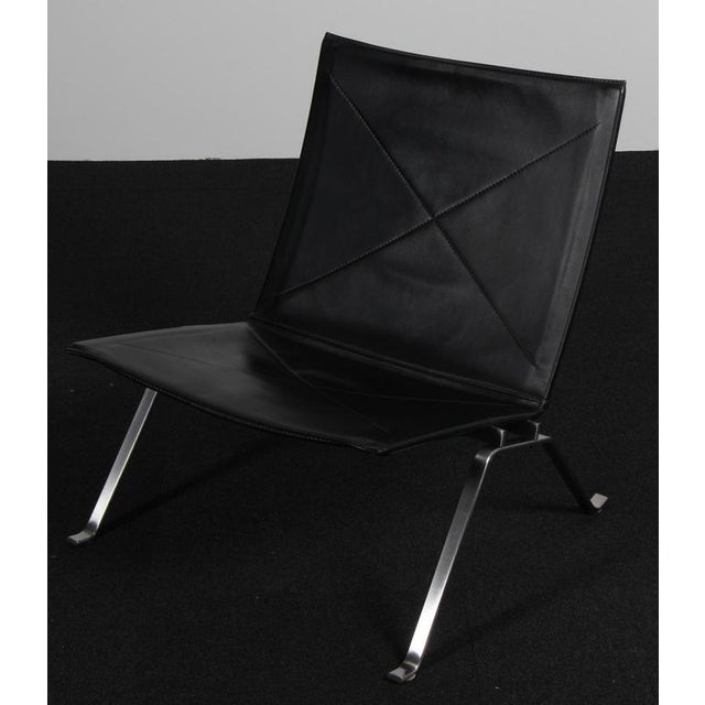 Poul Kjærholm lounge chair in original black leather. Frame of brushed steel. Model PK22, made by Fritz Hansen. This piece...