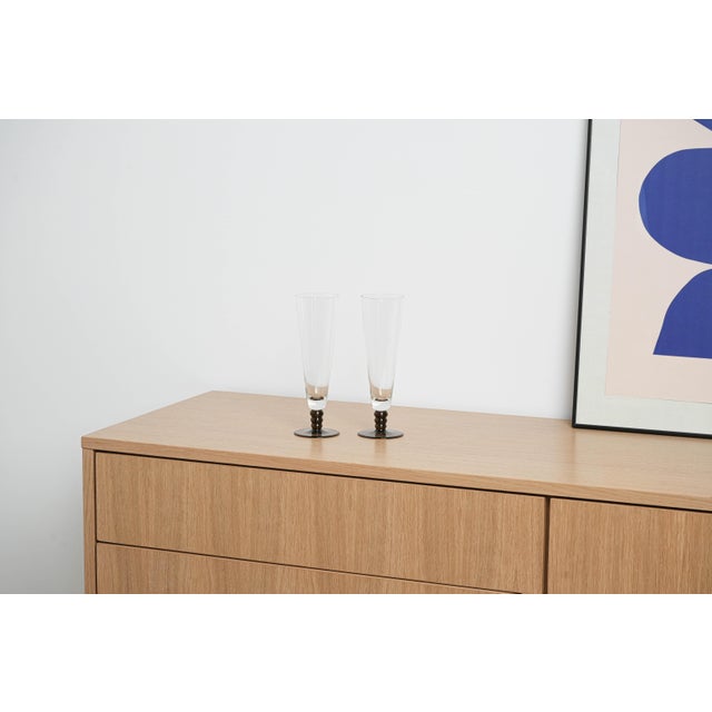 The pair of champagne glasses was manufactured in Italy in the 1970s. Elegant glasses with a transparent bowl and a dark,...