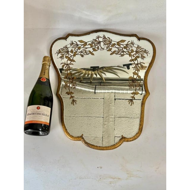 This is a very beautiful mirror, a 1940s-1950s decorative piece. The frame is covered in gilded wood, and the mirror is...