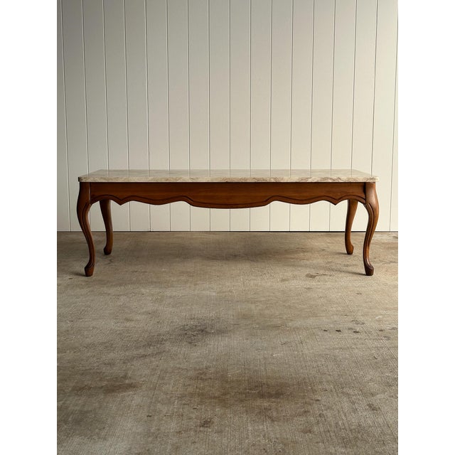 A beautifully proportioned French Provincial coffee table dating to the 1950s, featuring an exceptional marble top resting...