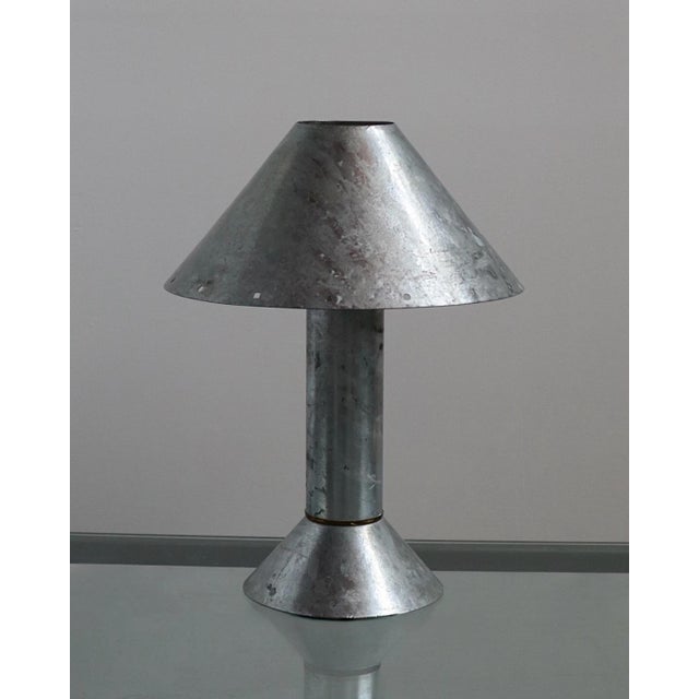 Postmodern table lamp by Ron Rezek, circa 1980s. The galvanized steel frame features a removable outer shade accented by a...