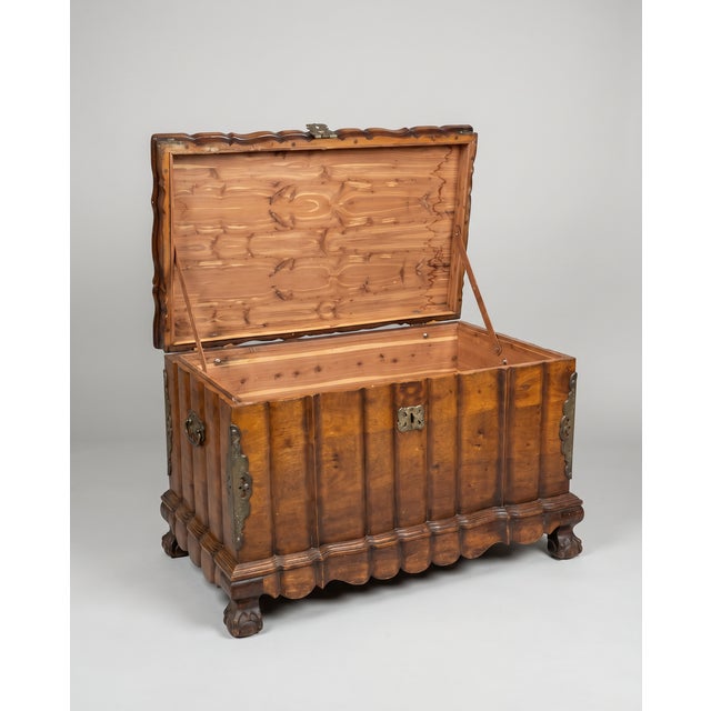 A beautifully crafted antique blanket chest featuring rich wood grain, hand-carved paneling, and striking original iron...
