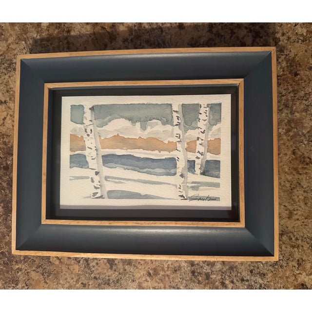 This modern, stylized winter scene features tall birch trees set against soft layers of icy blues, warm neutrals, and...