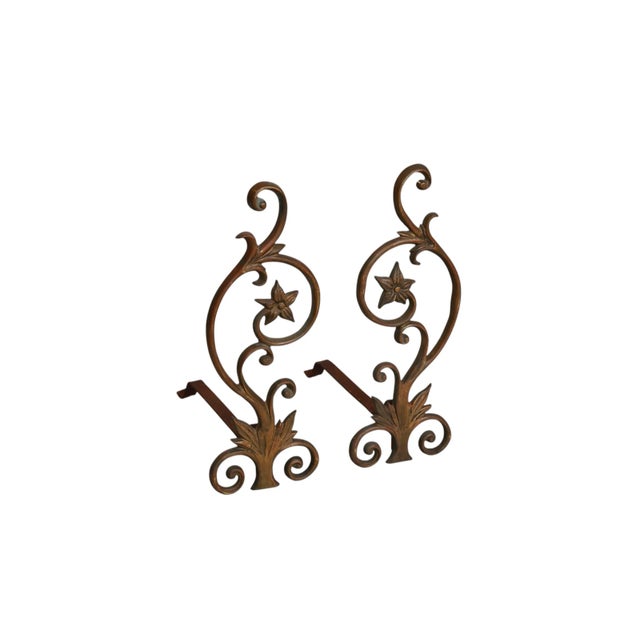 A pair of art nouveau period bronze andirons. Large C-scrolls are each adorned with a five-pointed flower and blades of...