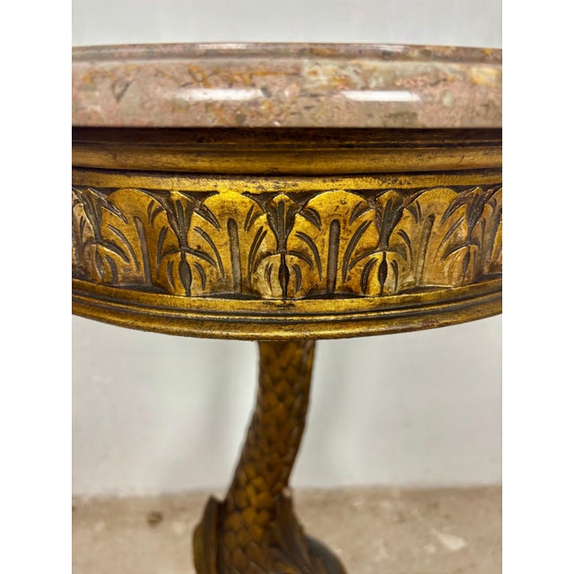 Elegant polychromed pedestal side table featuring a sculptural carved base and circular marble top. The table stands on an...