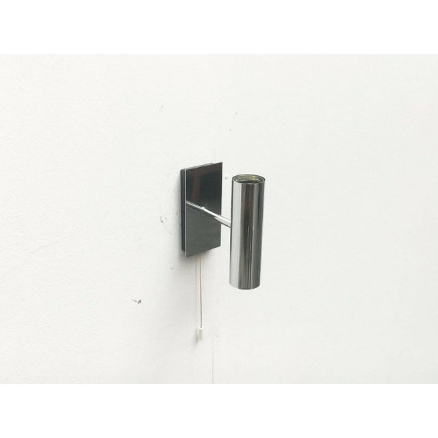 Simple wall light from Hustadt Leuchten. Simple cylindrical shape and colored in chrome. The black mounting plate is...