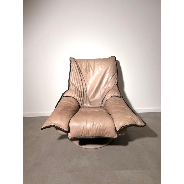 Striking vintage lounge chair upholstered in soft beige leather with contrasting dark brown leather piping. The generously...