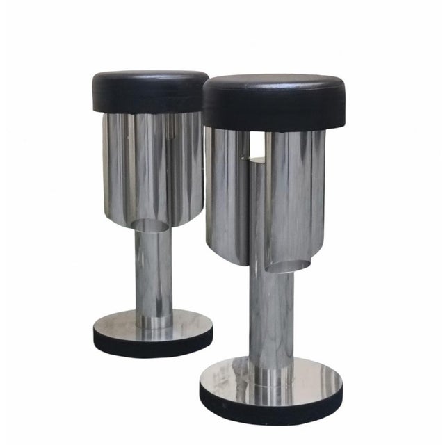 Pair of tall bar stools made in Italy in the 1970s. Steel frame, padded seat covered in black imitation leather. They have...