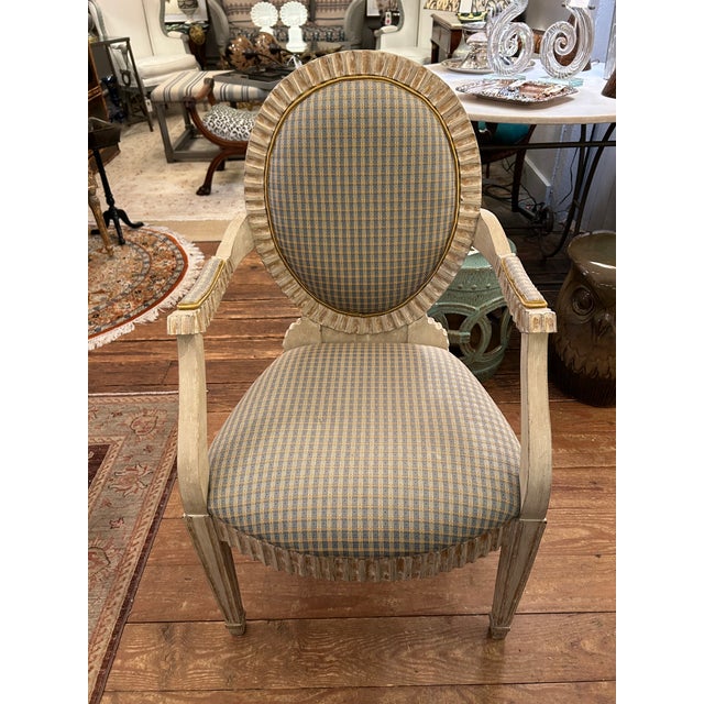 Luxurious vintage pair of antiqued painted carved wood bergeres having lovely pale blue and cream plaid upholstery. The...