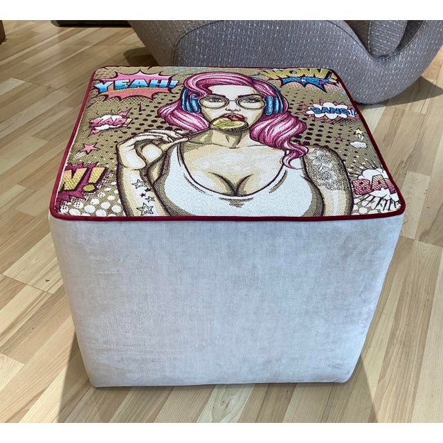 Contemporary design pouf with a seat upholstered in jacquard fabric decorated in a Pop Art/comic style, depicting a female...