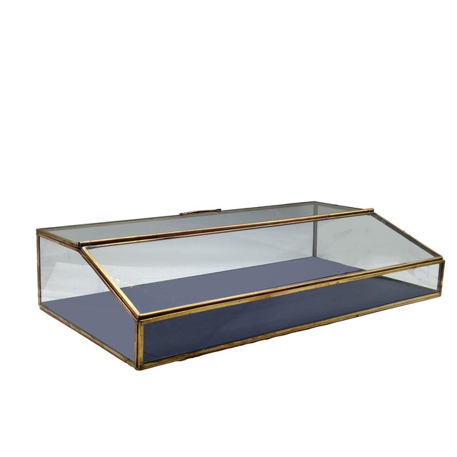 Tabletop display case with brass frame, often used as a jewelry box or to display and store decorative items. It features...