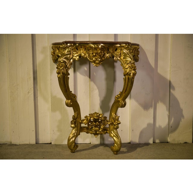 A louis xv style wall console table in carved and gilded wood, adorned with a central mascaron and rich foliate...