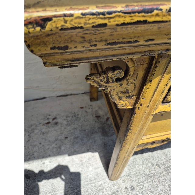 Impressive antique Asian entre table handcrafted in hardwood with two drawers and carved spandrels painted in a mustard...