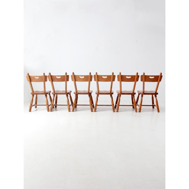 This set of six vintage maple dining chairs by Willett Furniture features a classic Early American silhouette with turned...