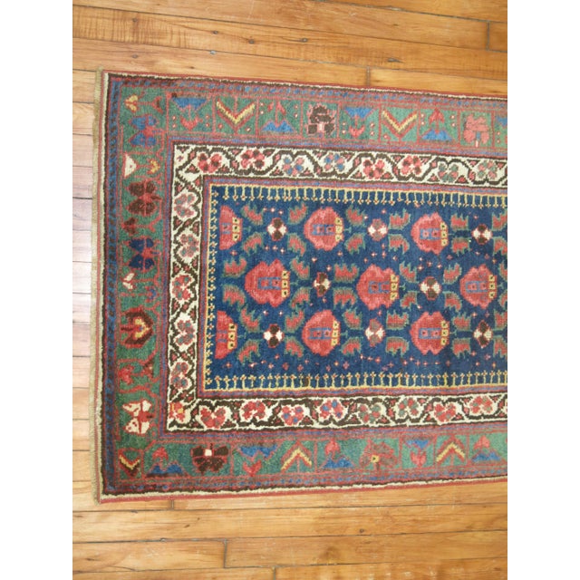 A narrow and long Persian runner with a floral design on a navy field, the border is green. Lot of different accent...