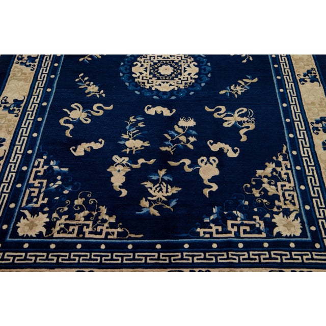 This luxurious antique Peking Chinese hand knotted wool rug features a navy blue field adorned with a designed frame and...
