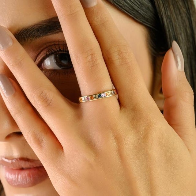 This contemporary eternity band showcases 13 princess-cut, multi-colored sapphires totaling 1 carat, set in 14K yellow...