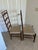 These are vintage Shaker-style ladder-back chairs, characterized by their high, slatted backs and hand-woven checkerboard...