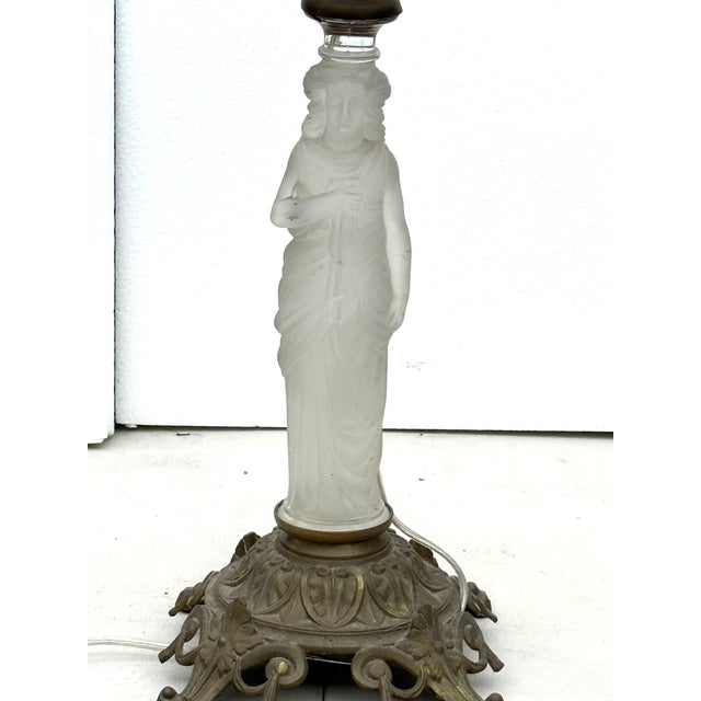 This elegant French-style table lamp features a beautifully sculpted frosted-glass figure standing atop an ornate cast-...