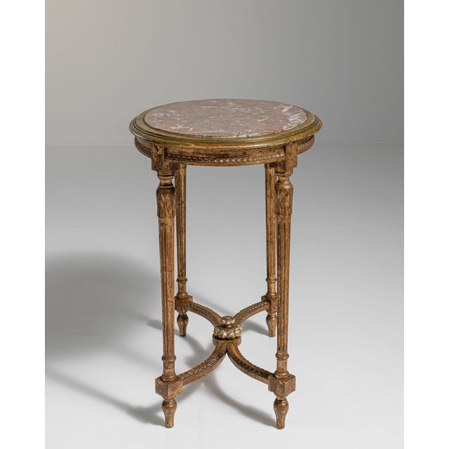 Carved giltwood gueridon table in Antique Gold Giltwood. The antique gold giltwood surface highlights oval marble top,...