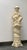 An almost life size, white ceramic statue of a chinoiserie musician with flute on a pedestal. Seated crosslegged he is...