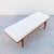 A restored entryway or bed-end bench in solid ash wood with tufted velvet upholstery, made in the United States c. 1960s....