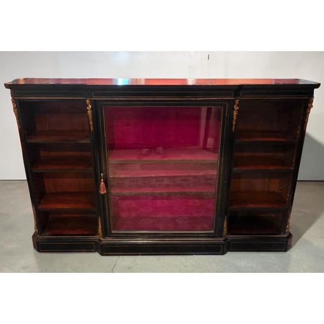 A striking and highly architectural Victorian ebonized display side cabinet, retailed by the esteemed London firm Edwards...