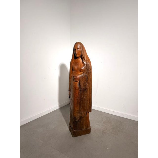 An expressive wooden sculpture by Rutger Rosier , depicting a standing female figure with long flowing hair and a serene,...