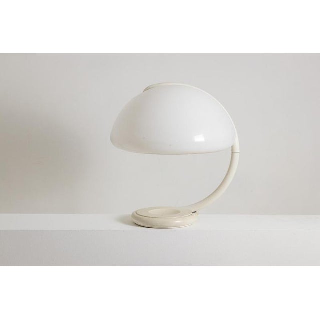 Elio Martinelli. “Serpente” table lamp, made of white-lacquered metal with a white opal methacrylate shade. Iconic model....