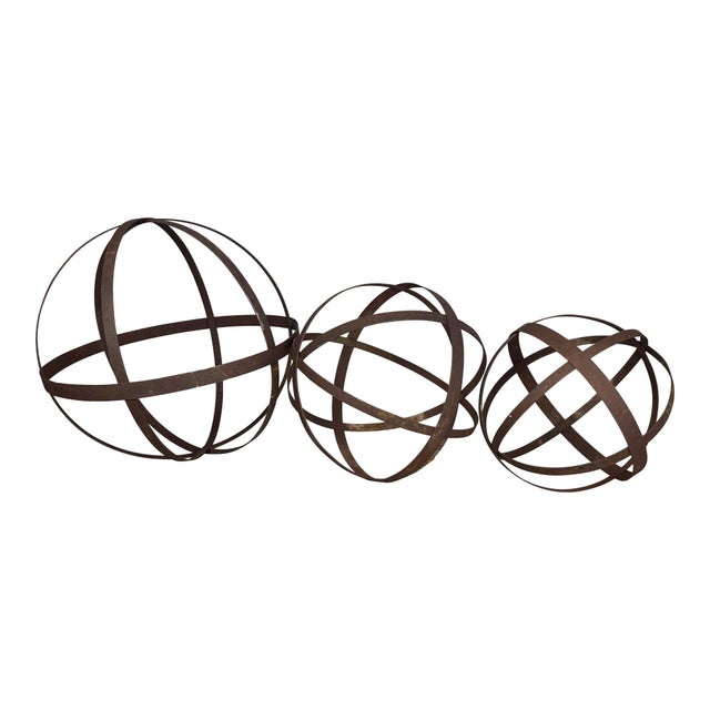 A sculptural trio of cast iron garden spheres, each formed from intersecting iron bands creating an openwork orb...