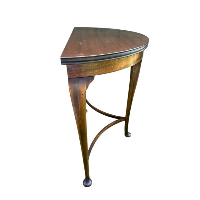 A beautifully preserved early-20th century petite demilune table with delicately arched horizontal stretchers and Queen...