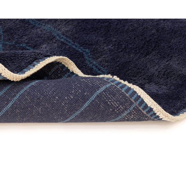 A rug that reads like moonlight on deep water — a dense, mottled navy field traced with a fine cerulean blue lattice...