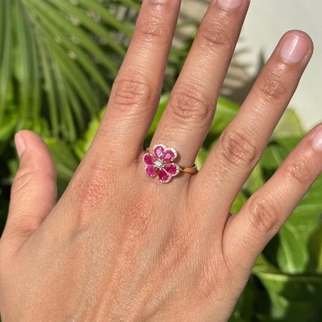 This elegant floral cocktail ring features 1.18 carats of vivid rubies, crafted in 14K yellow gold. The rubies measuring...
