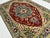 This hand-knotted Heriz rug features a bold stepped diamond medallion in deep red and slate blue, set against an ivory...