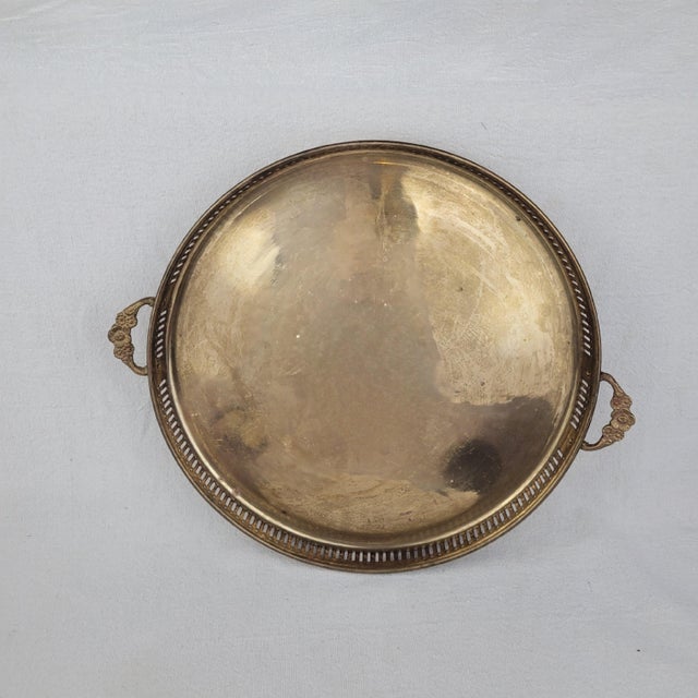 Vintage round brass gallery tray features an elegant pierced railing and ornate floral-detailed handles. The polished...