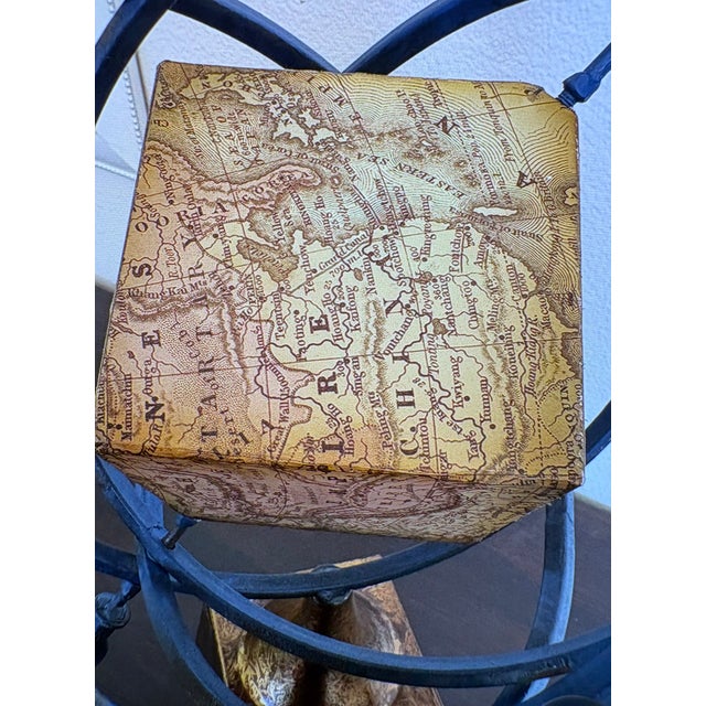 This blue and golden armillary sphere has a globe in the center of it in the form of a square, representing the world,...