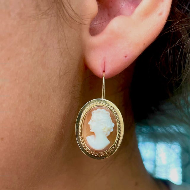 This is part of Chairish’s Fine Jewelry assortment. This a fine pair of carved shell cameo earrings mounted in 14K gold...