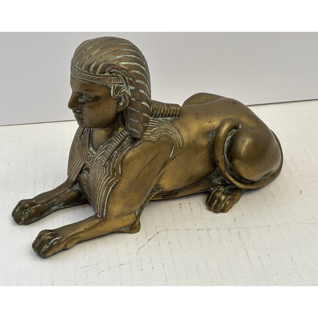 Bronze figure of a sphinx from early 1900's characterized by its detailed pharaonic headdress and recumbent posture