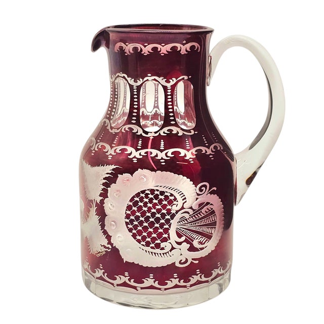 A ruby glow, deep and resonant, holds the quiet tale of artisans in Bohemia. This hand-blown Egermann pitcher, cut to...