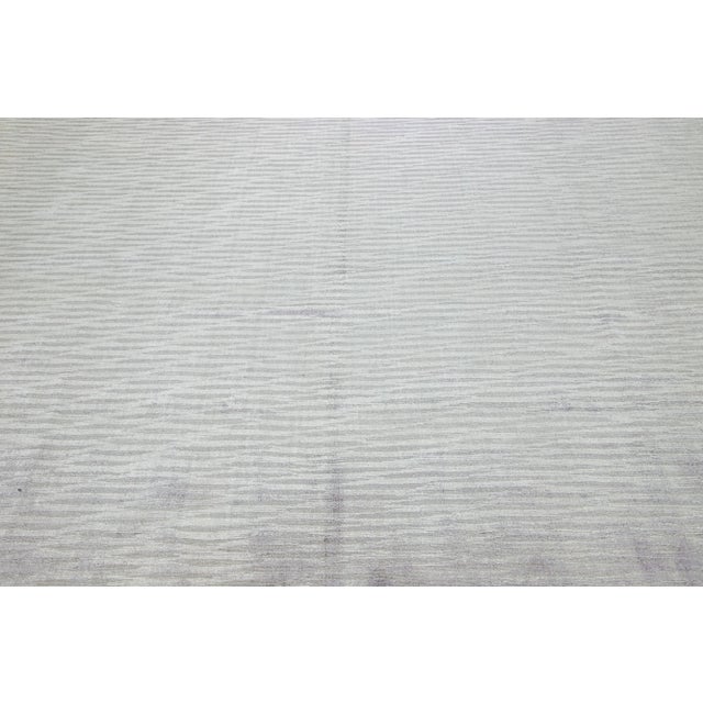 This exquisite contemporary wool and silk rug showcases a striking gray-silver base adorned with a stunning geometric...