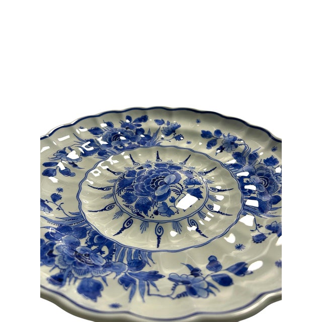 A vintage hand-painted royal delft wall plate by de porceleyne fles. The plate has a fluted, scalloped form with a raised...