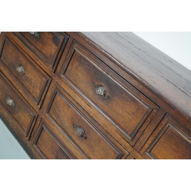 This apothecary cabinet was made in the early 20th century in France from oak and fruitwood. It features 9 large drawers...