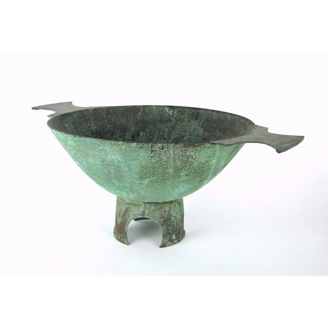 A large and sculptural double-handled centerpiece bowl in copper metal with an encrusted verdigris green patina by Marie...
