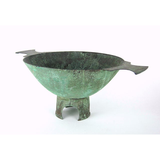 A large and sculptural double-handled centerpiece bowl in copper metal with an encrusted verdigris patina in dark green by...