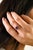 This delicate floral cluster ring features a vibrant round blue sapphire at the center, surrounded by charming halo of...