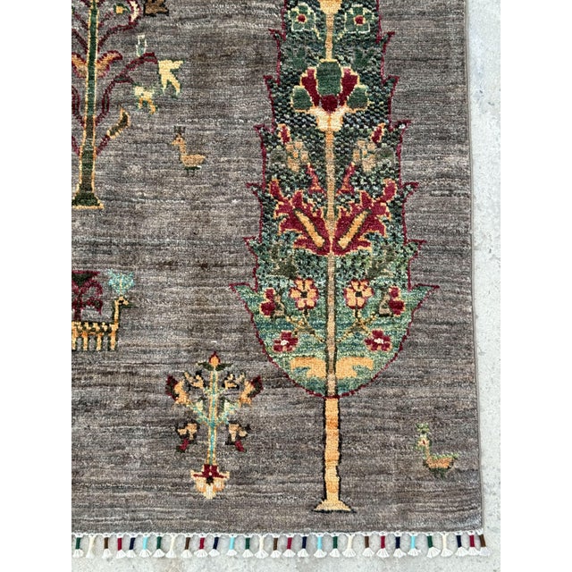 A hand-knotted rug woven in Afghanistan on a charcoal grey ground, planted with a grove of cypress and flowering trees in...