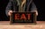 Charming countertop lighted sign featuring bold red "EAT" lettering over "GOOD FOOD" in gold, flanked by stylized steam...