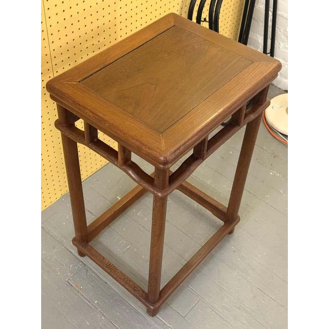 A mid-century accent table with a rectangular top, minimalist profile, and subtle openwork geometric detailing beneath the...