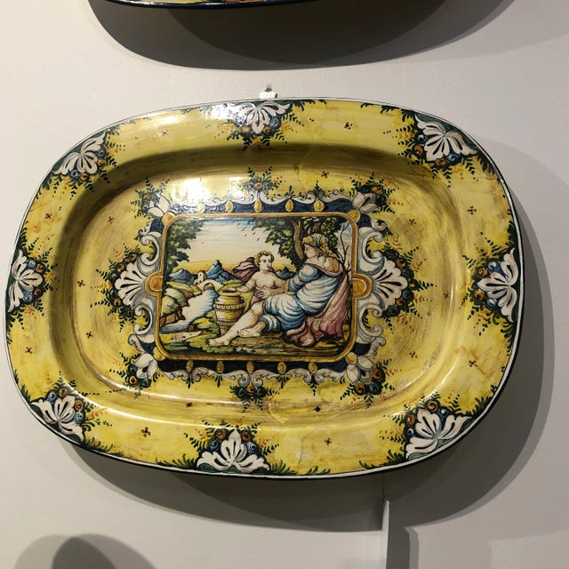 Hand painted ceramic wall plate featuring woman and child by stream in yellow and blue colors. Hand made items may vary in...